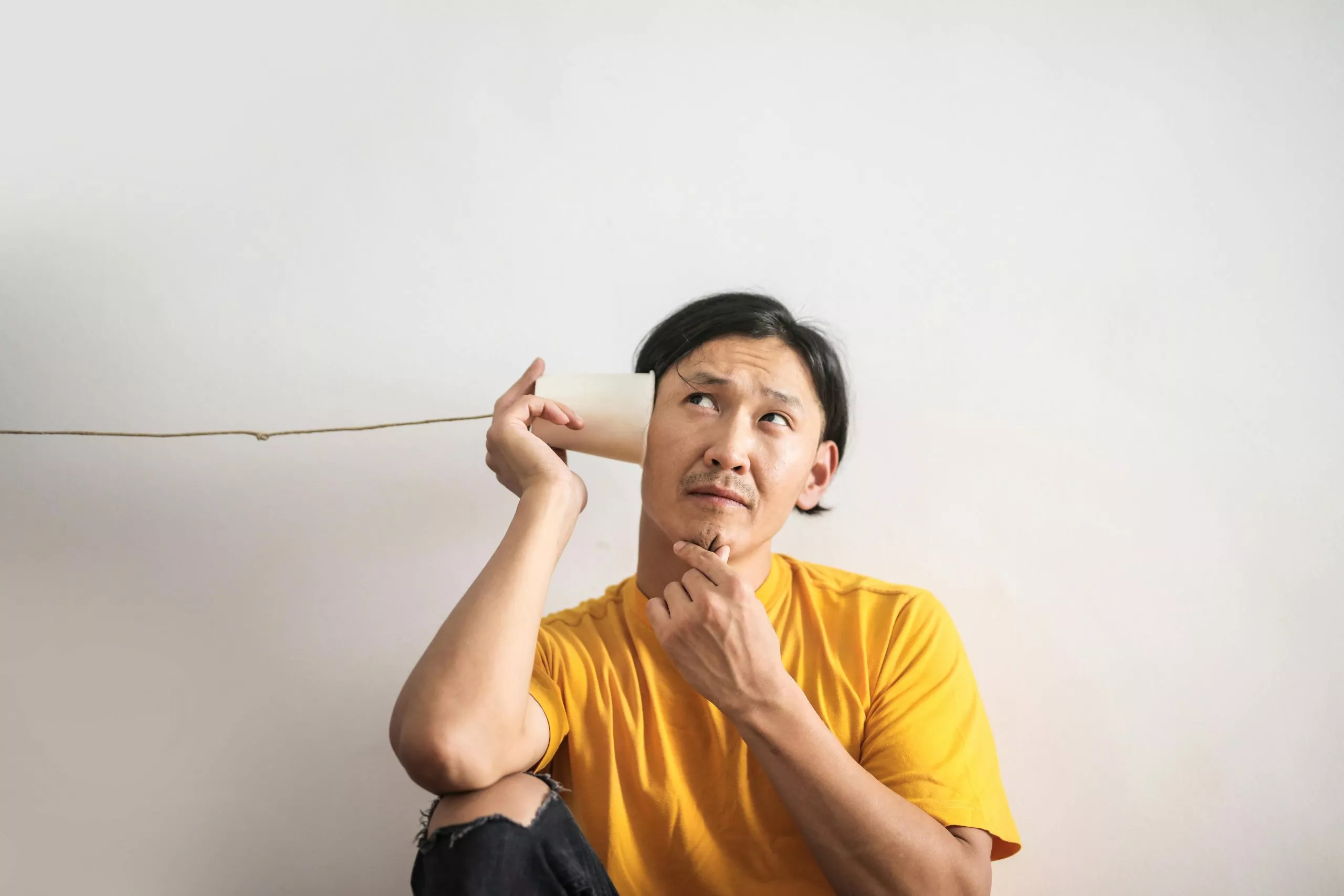 Person with cup to their ear listening in